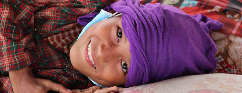 Photo of young smiling Nepalese girl lying on pillow